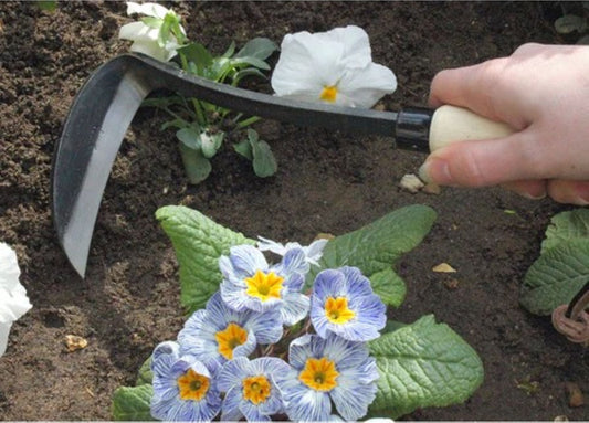 Luking i blomsterbed med lukeverktøy og knepute i hagen
