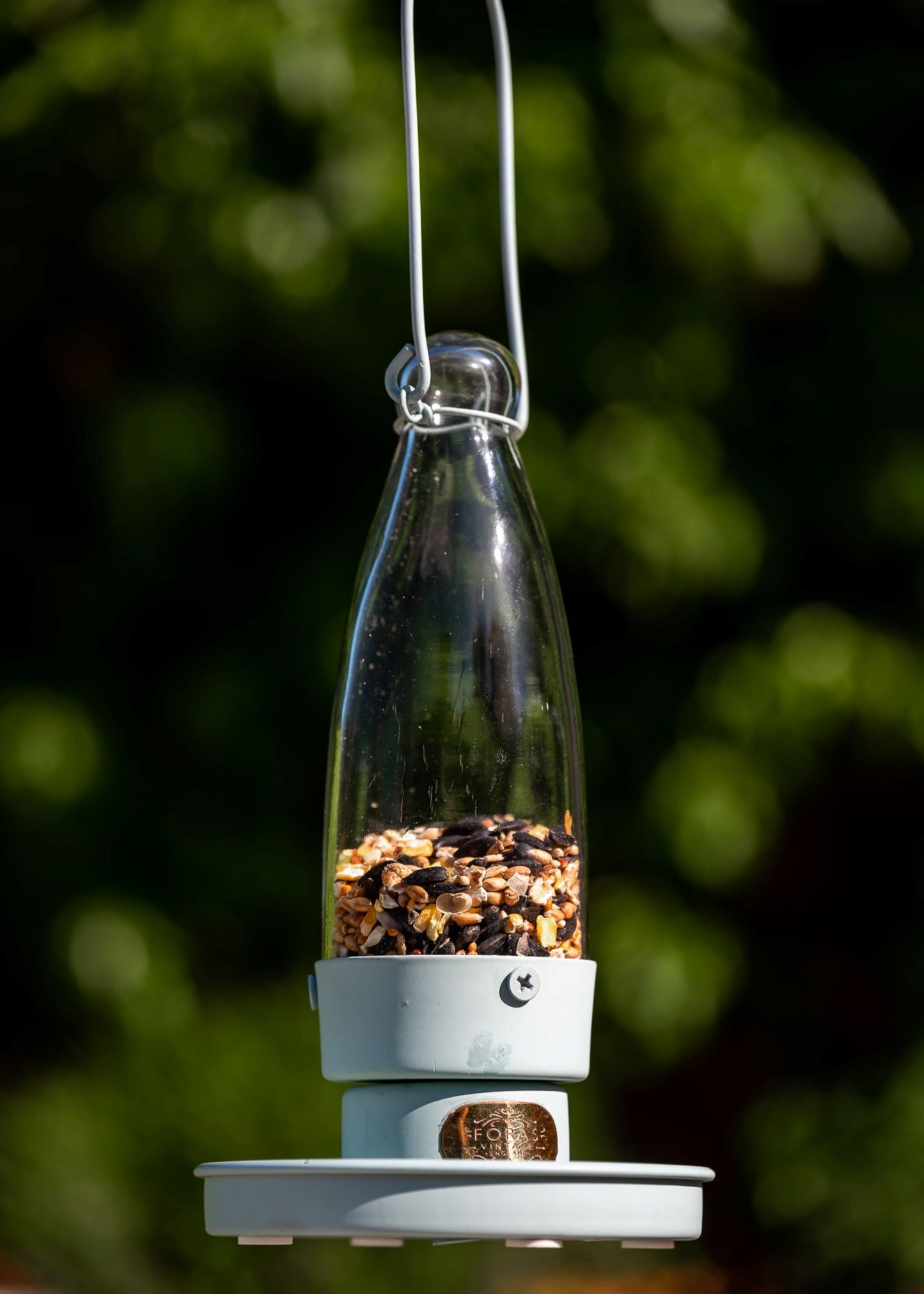 Stilren grønn fuglemater i metall og glass, henger i hage