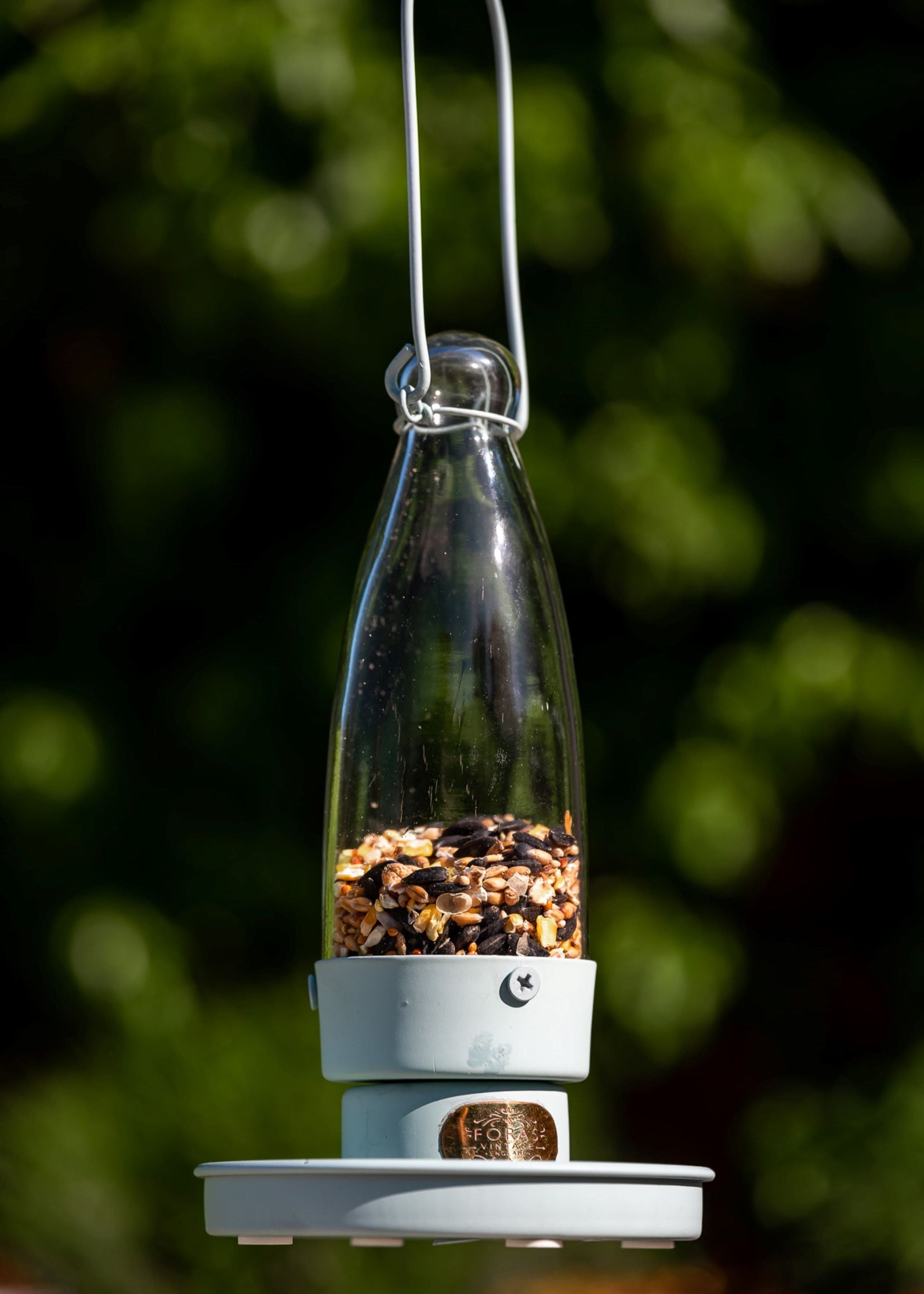 Stilren grønn fuglemater i metall og glass, henger i hage