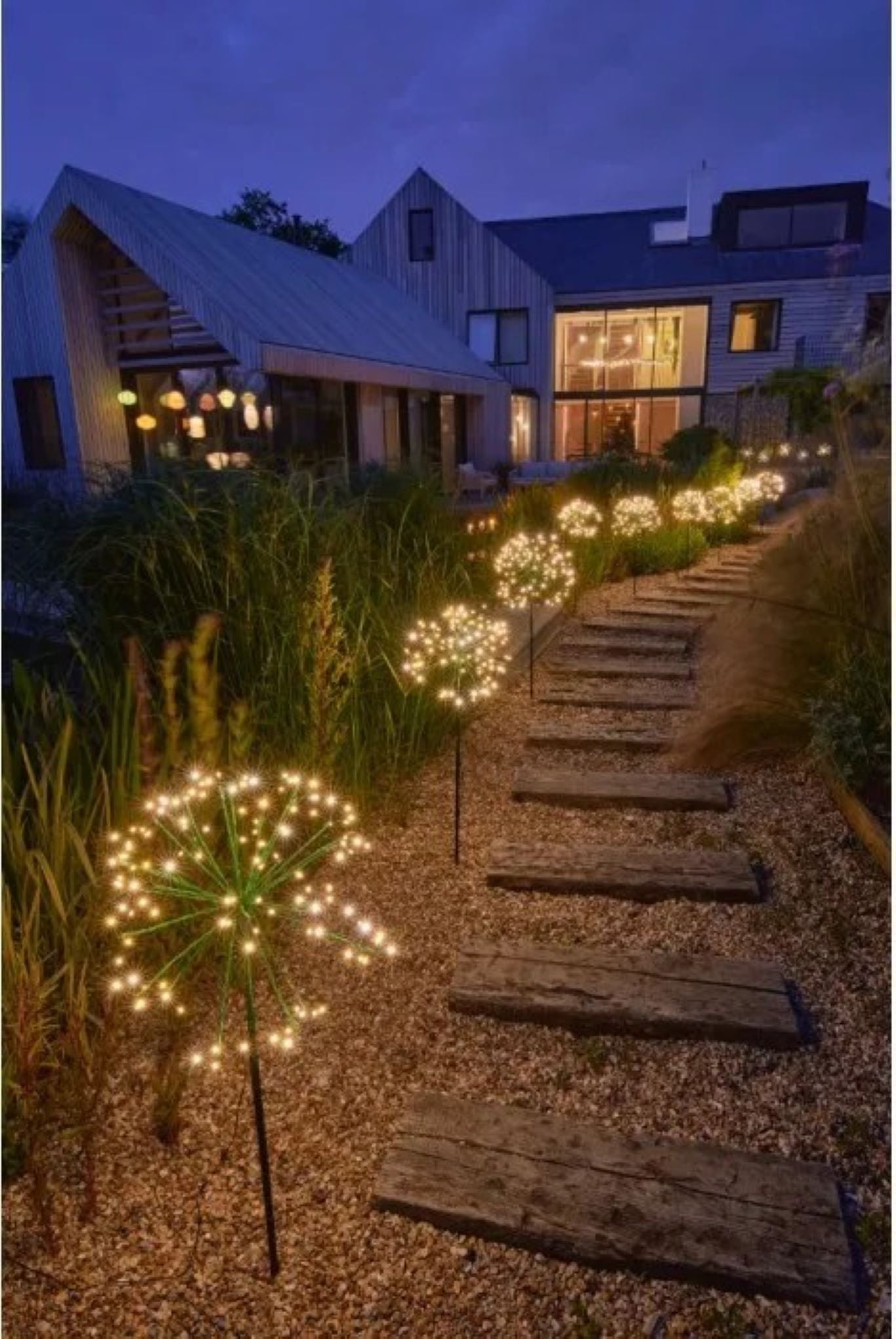 flere store dandelion solcellelanterner i hage som gir glitrende belysning