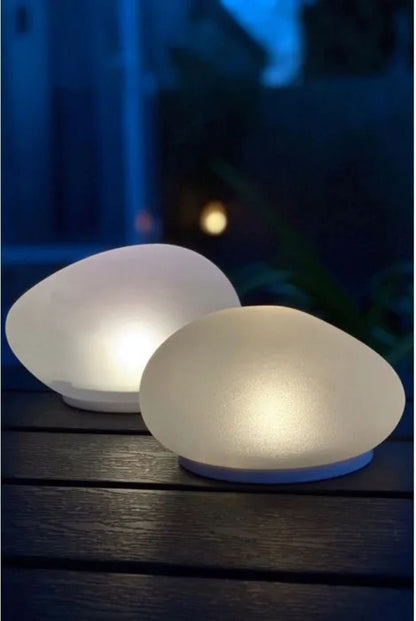 solcellelanterner i hvitt glass på terrassebord som gir lun og dekorativ utebelysning